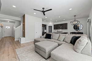 Living area with a chandelier, recessed lighting, light wood-style flooring, and a ceiling fan