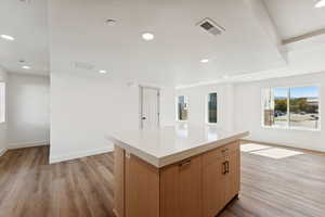 Kitchen with light countertops, a kitchen island, light wood finished floors, open floor plan, and recessed lighting