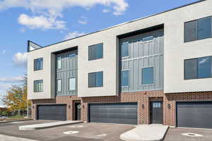 Contemporary home featuring board and batten siding, brick siding, an attached garage, and driveway