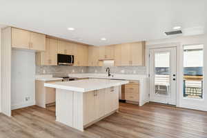 Kitchen featuring light brown cabinets, a center island, light wood-style flooring, modern cabinets, and recessed lighting
