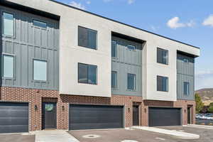 View of front of house featuring board and batten siding, brick siding, concrete driveway, and a garage