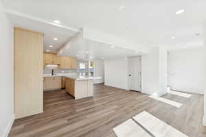 Kitchen featuring light brown cabinets, open floor plan, backsplash, light wood-style flooring, and recessed lighting