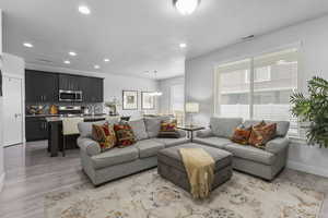 Living room featuring light wood-style floors, recessed lighting, a chandelier, and a textured ceiling