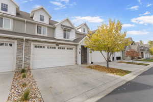Traditional-style home with a shingled roof, driveway, stone siding, a garage, and a residential view