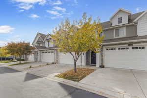 Traditional-style house with a shingled roof, driveway, stone siding, and a garage