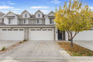 Traditional-style house with stone siding, concrete driveway, an attached garage, and roof with shingles