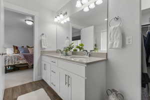 Ensuite bathroom featuring double vanity and wood finish floors