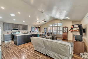 Living room with vaulted ceiling, a barn door, wood finished floors, a gasfireplace, and recessed lighting