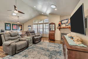 Living room with vaulted ceiling, a barn door, wood finished floors, a gas fireplace, and recessed lighting