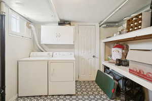 Laundry room with washing machine and dryer, tile patterned floors, and cabinet space