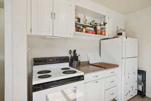 Kitchen with white appliances, white cabinetry, open shelves, and wood finished floors