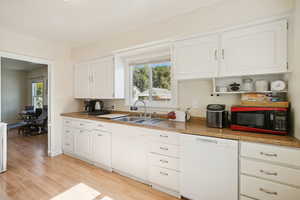 Kitchen featuring dishwasher, light wood-type flooring, white cabinetry, and open shelves