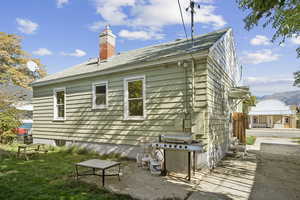 Back of house featuring a chimney, a mountain view, and a patio