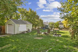 Fenced backyard featuring an outdoor fire pit, an outdoor structure, a patio, a garage, and a trampoline