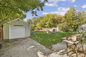 Fenced backyard with an outdoor structure, a garage, driveway, and a patio