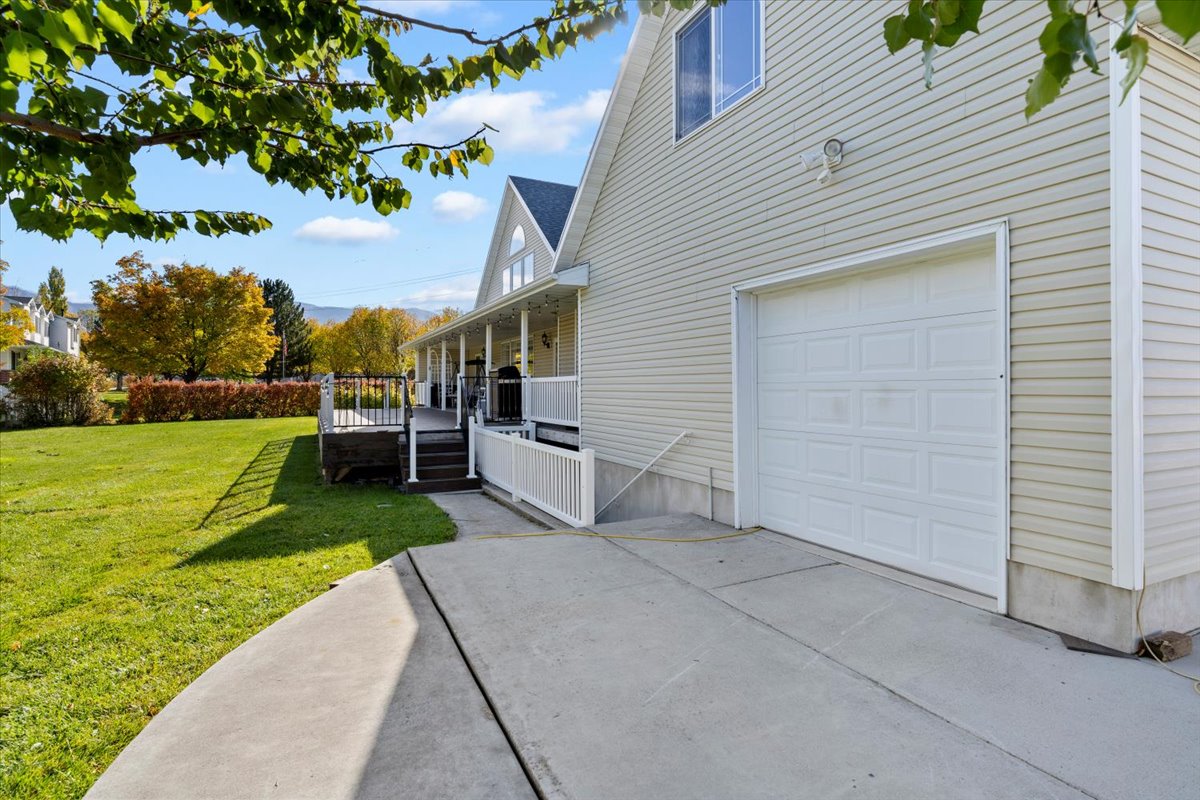 View of side of property with a lawn, covered porch, and driveway