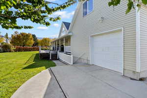 View of side of property with a lawn, covered porch, and driveway