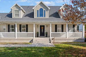 View of front of home with roof with shingles, a porch, and a front yard