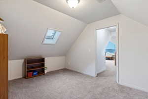 Bonus room featuring lofted ceiling, light colored carpet, and a skylight
