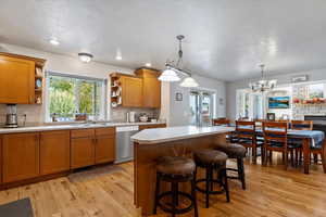 Kitchen featuring brown cabinetry, light countertops, a breakfast bar, light wood-style flooring, and pendant lighting