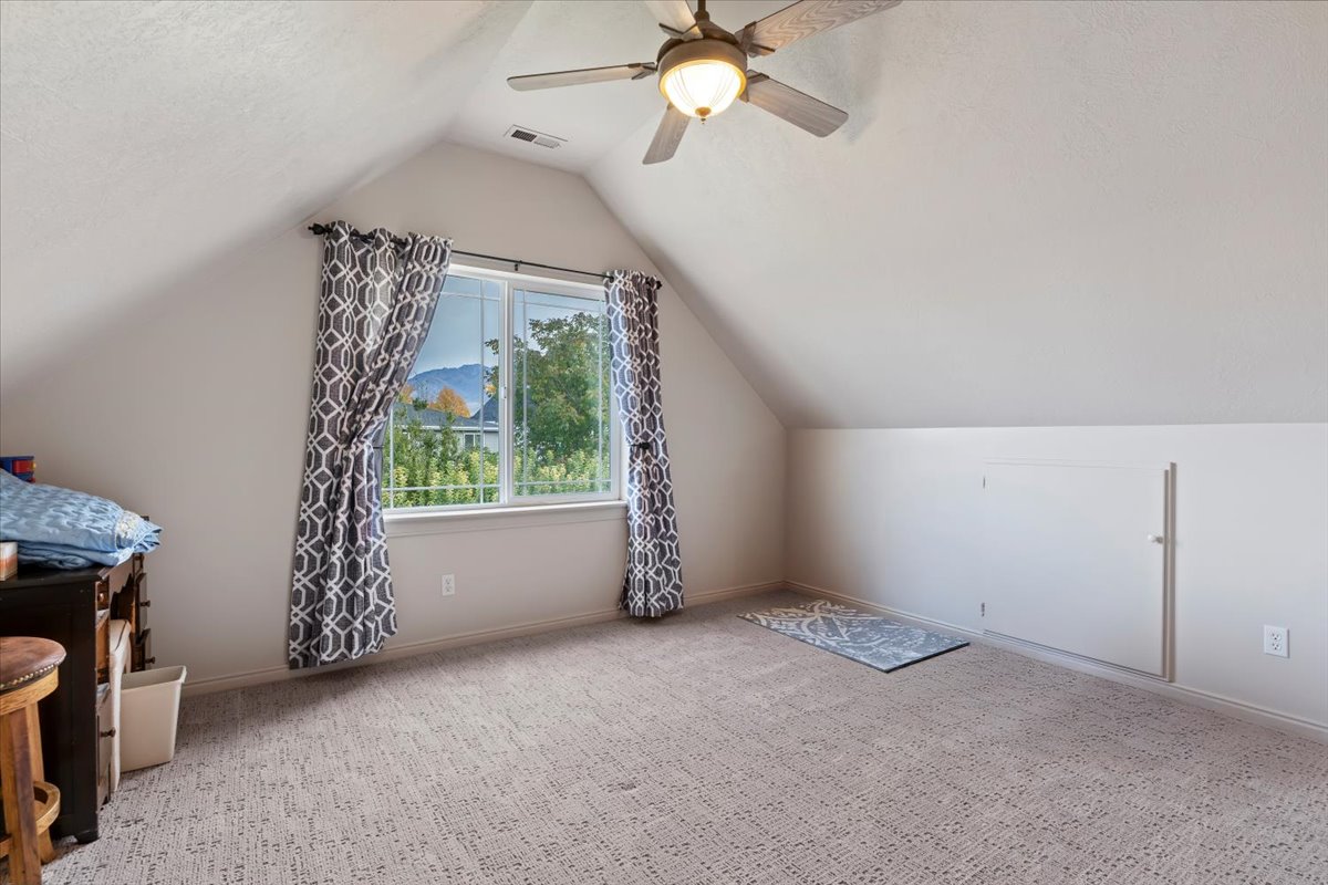 Bonus room with vaulted ceiling, carpet flooring, ceiling fan, and a textured ceiling