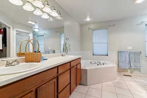 Bathroom with light tile patterned floors, a garden tub, and double vanity
