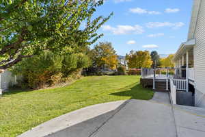 View of green lawn featuring a patio and a deck