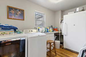 Laundry area with light wood-type flooring and separate washer and dryer