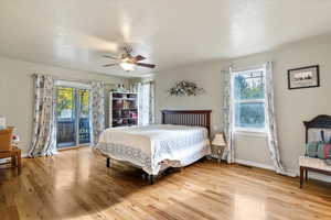 Bedroom featuring access to exterior, light wood-style floors, a ceiling fan, and a textured ceiling