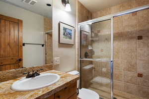 Full bathroom featuring a textured wall, vanity, and a stall shower
