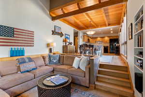Living room featuring a wooden ceiling with exposed beams, light wood-type flooring, and wood walls