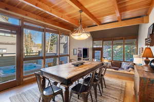 Dining space with light wood finished floors and a wooden ceiling with exposed beams