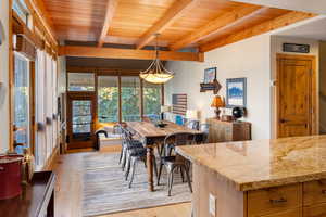 Dining space with light wood finished floors and a wood ceiling with exposed beams