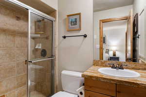 Ensuite bathroom featuring a stall shower, a textured wall, and vanity