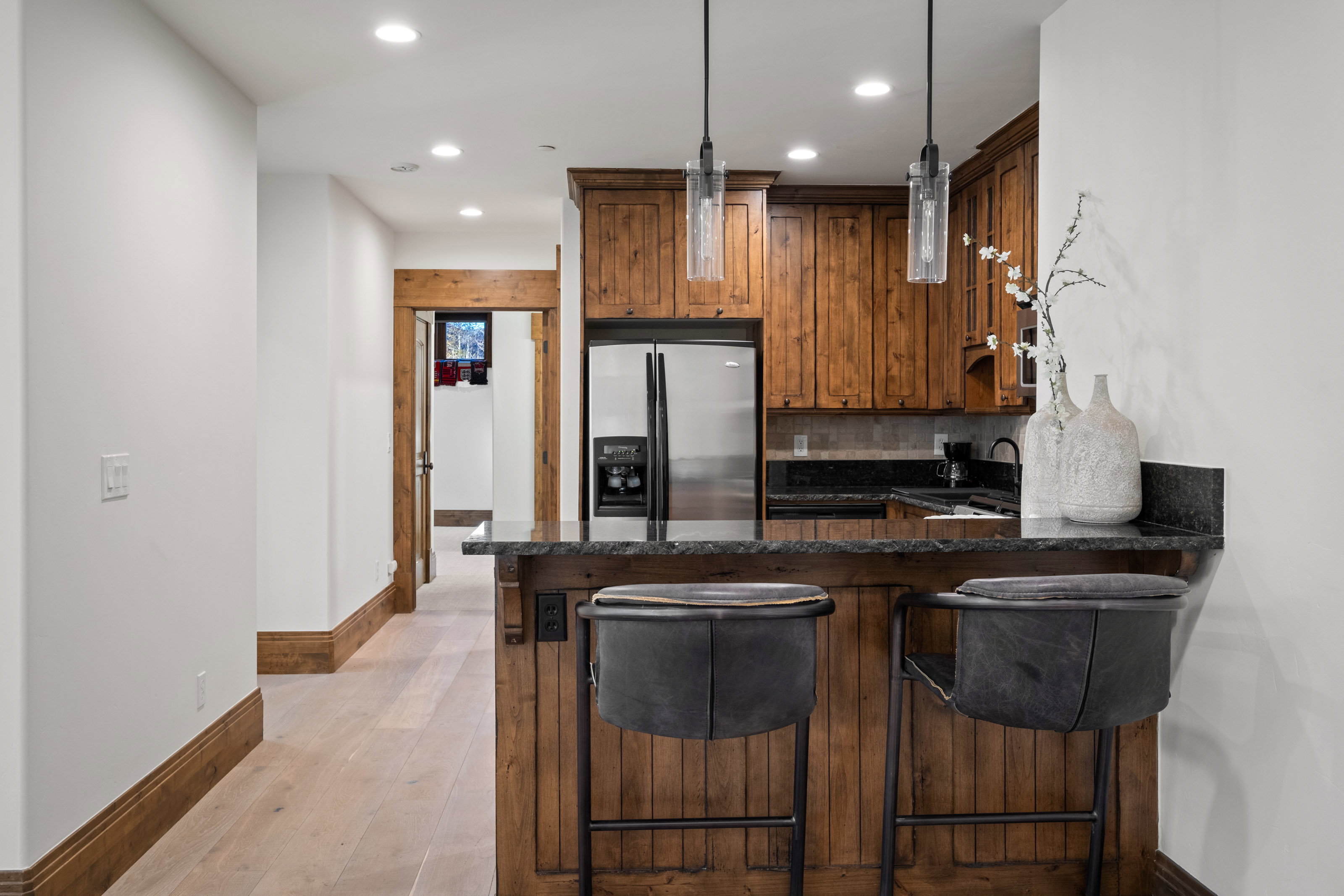 Kitchen featuring a kitchen breakfast bar, dark stone counters, stainless steel fridge, decorative backsplash, and wood finish cabinetry