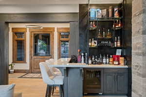 Indoor bar featuring open shelves, wine cooler, and light wood-type flooring