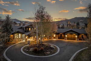 View of front of home featuring a mountain view, stone siding, and curved driveway