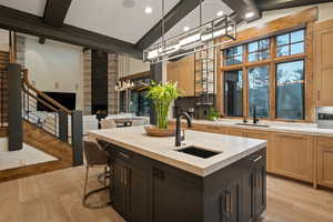 Kitchen featuring a breakfast bar area, an island with sink, pendant lighting, light wood finished floors, and dual tone cabinetry