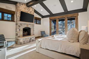 Carpeted bedroom featuring a stone fireplace, access to exterior, a baseboard radiator, and recessed lighting