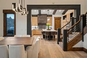 Dining room featuring beamed ceiling, light wood-style flooring, stairway, and recessed lighting