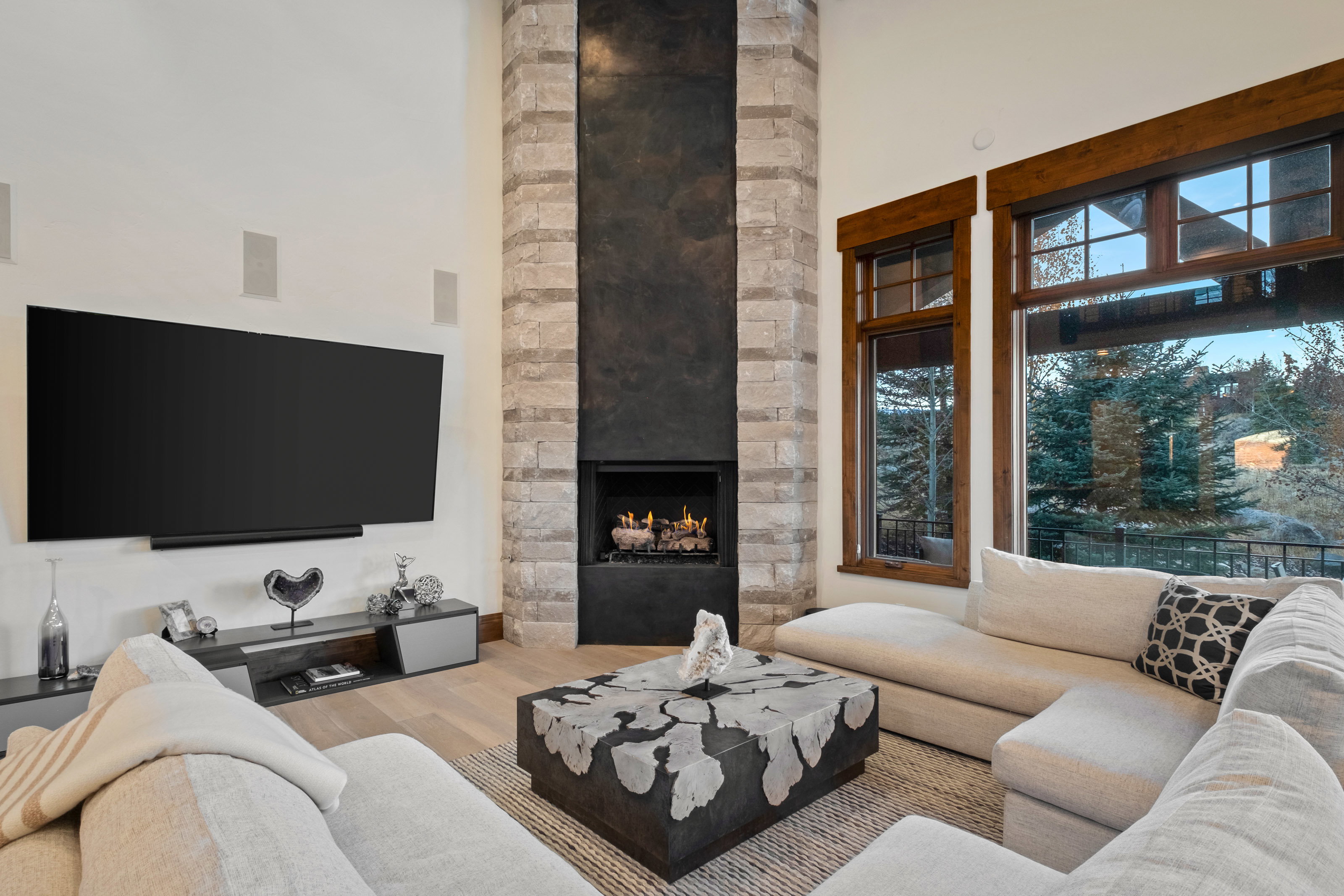 Living room featuring a high ceiling, light wood-style floors, and a stone fireplace