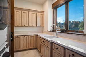 Kitchen featuring light stone countertops and stacked washing machine and dryer