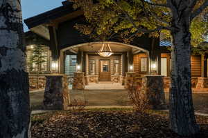 View of exterior entry featuring covered porch and stone siding