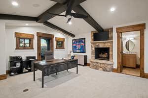 Office space with a stone fireplace, a ceiling fan, light carpet, recessed lighting, and vaulted ceiling with beams