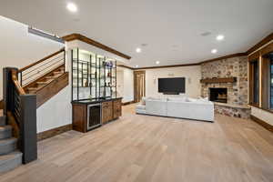 Unfurnished living room featuring a dry bar, light wood finished floors, beverage cooler, recessed lighting, and a fireplace