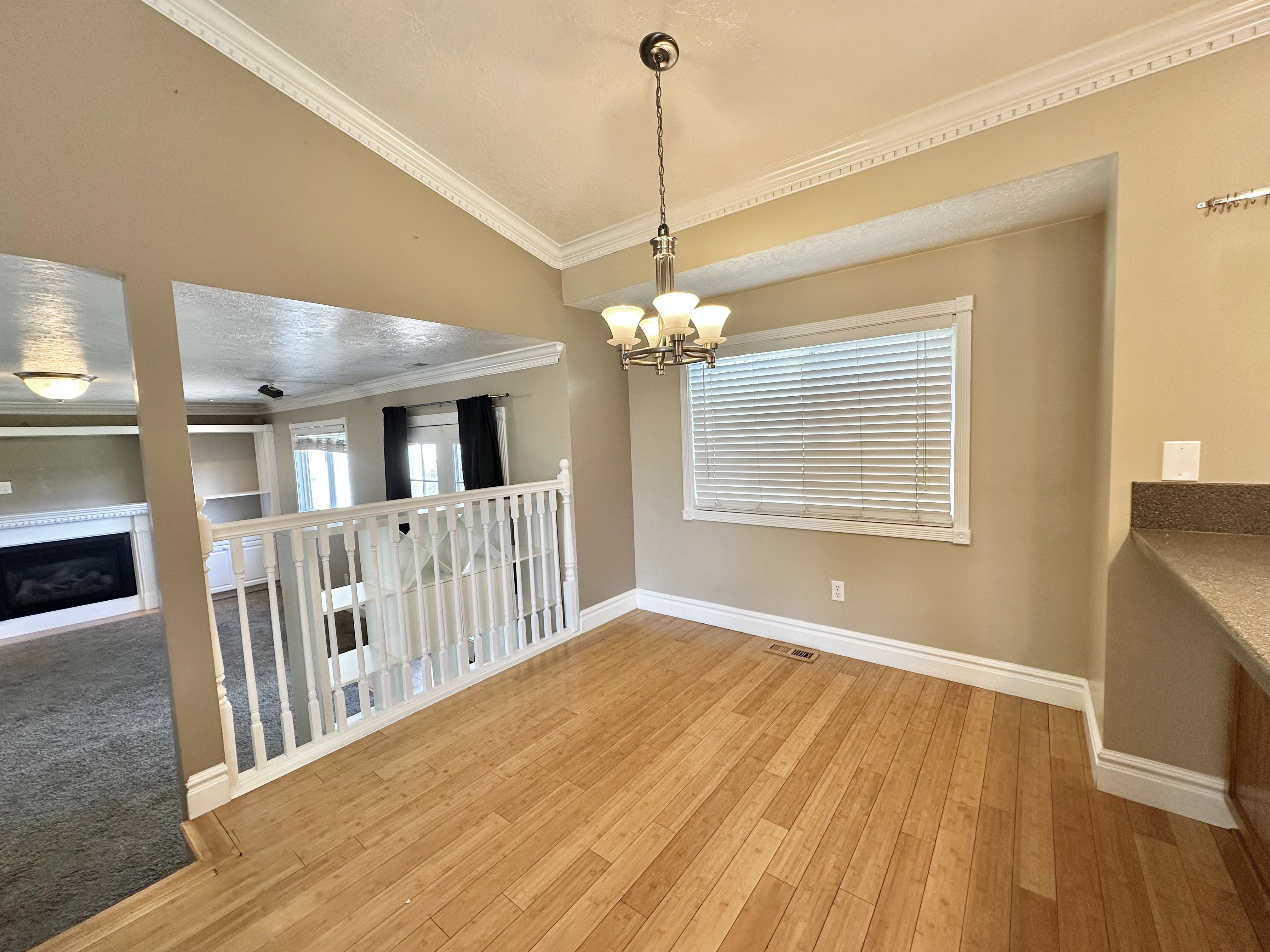 Dining area with chandelier, bamboo flooring, window with view to east mountain and back yard.