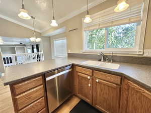 Kitchen featuring dishwasher, lighting, Corian counters, and view of greenery through window