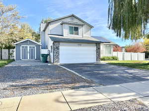 Traditional-style house featuring roof mounted solar panels, driveway, a garage.