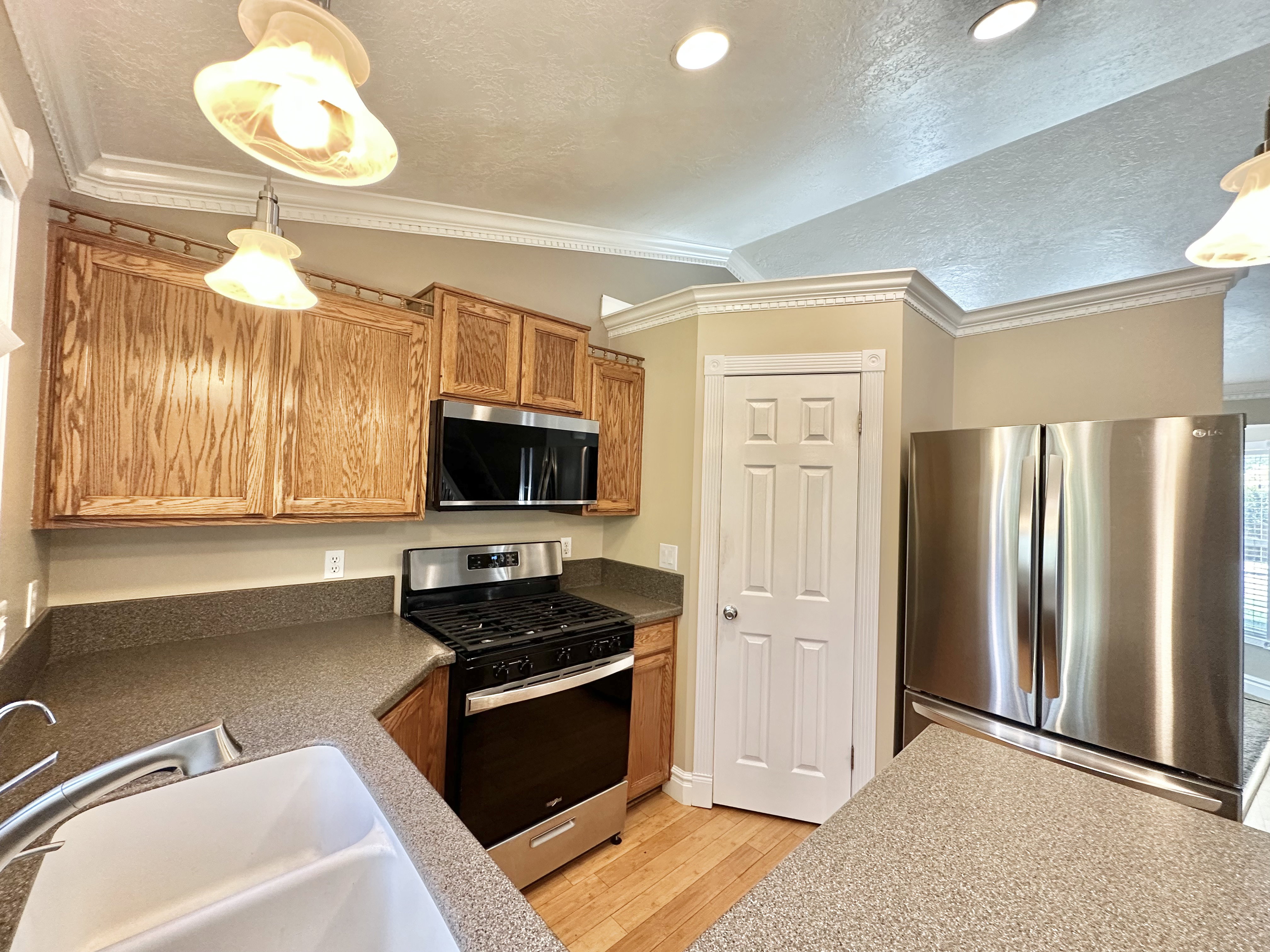 Kitchen featuring ornamental lighting, single surface Corian counters, new appliances, and pantry