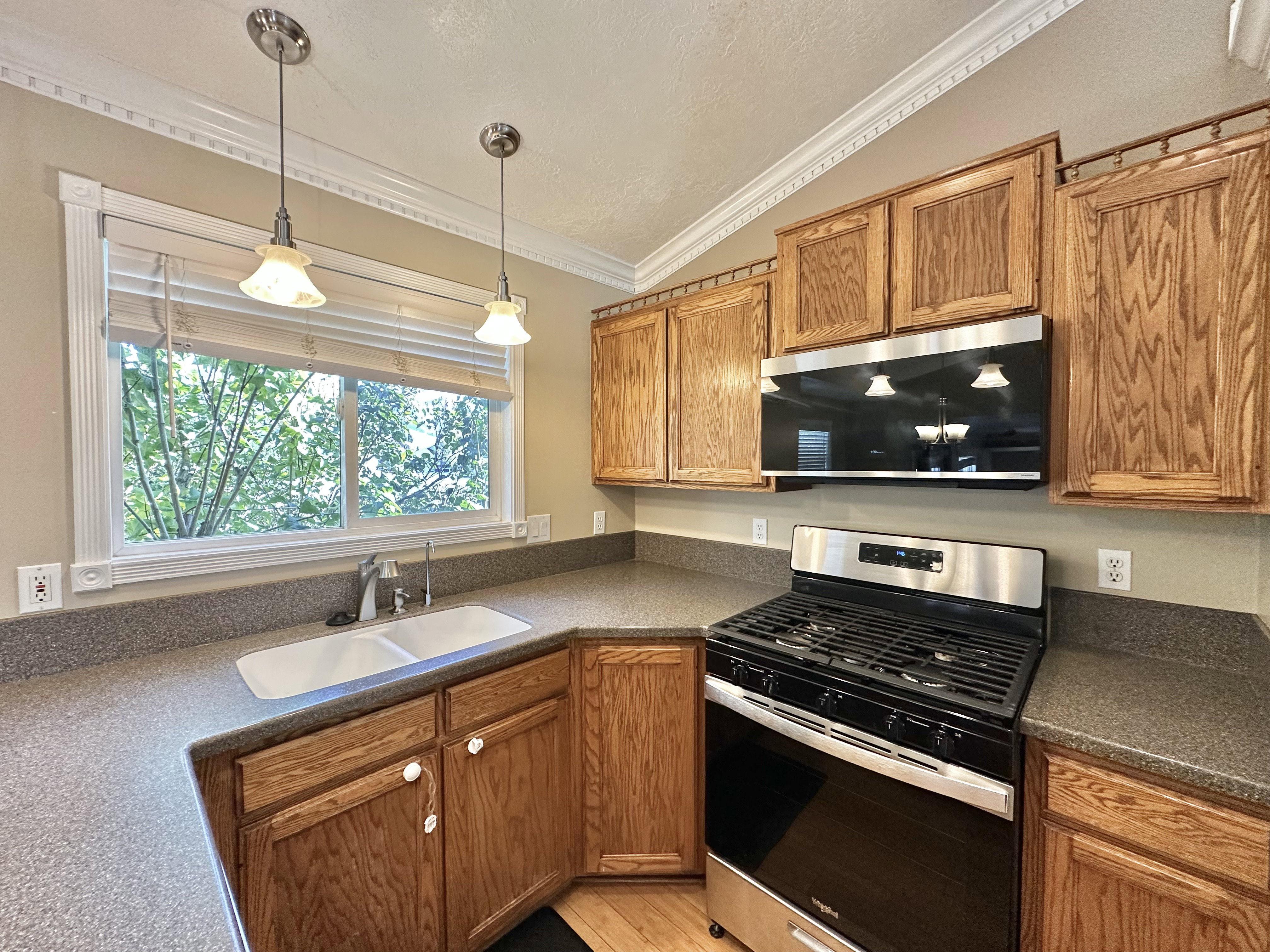 Kitchen view of GAS range/oven and microwave, lighting, sink, cabinets, window